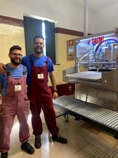 Two men standing next to winery equipment